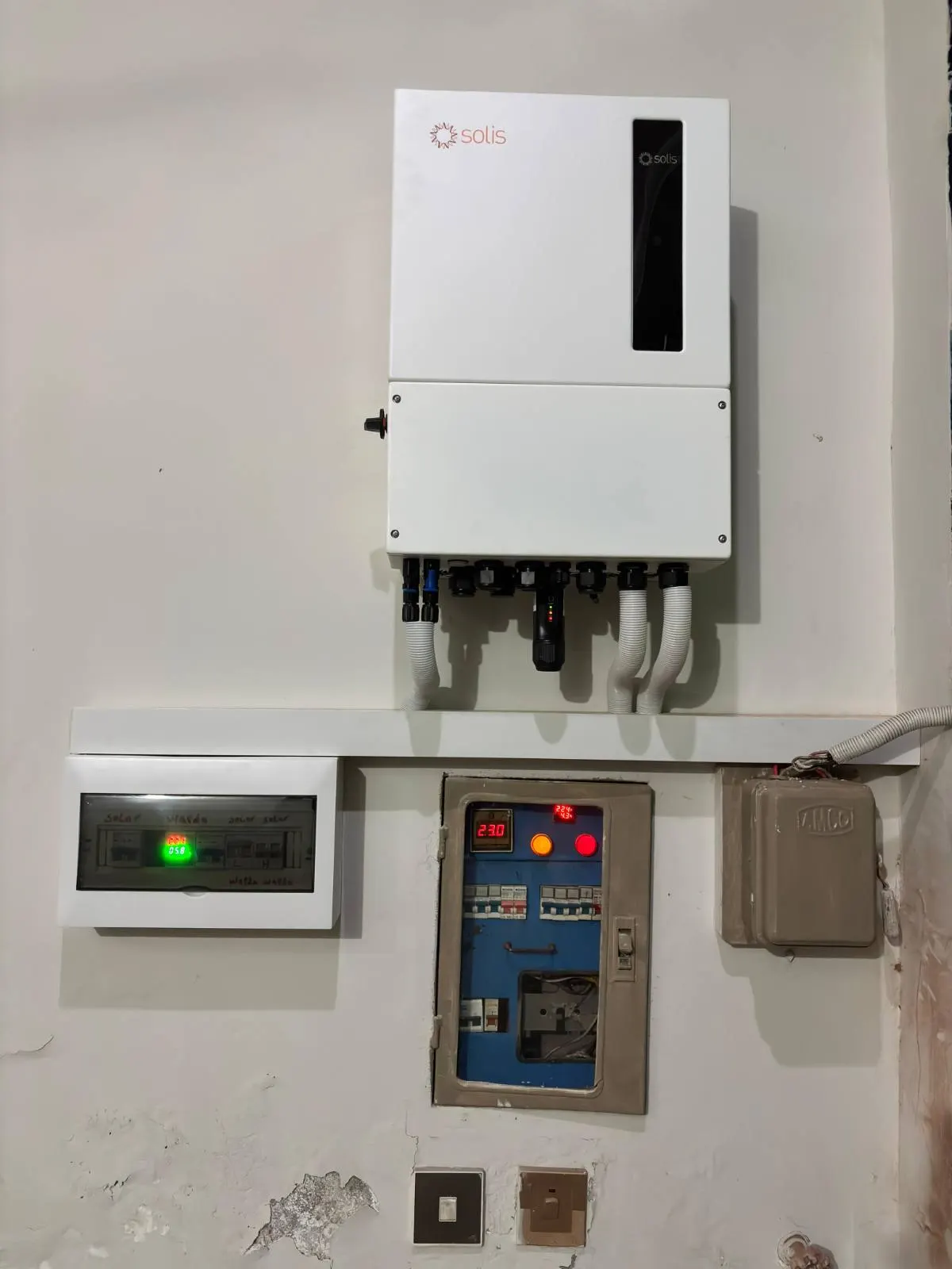 Hybrid inverter on a shelf with a meter and a red protection board below